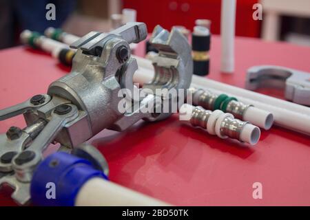 Water metal-plastic pipes and tools for press fittings on the table. Industry Stock Photo