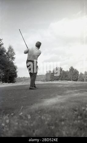 1960s, Out on a golf course, an adult male golfer on the fairway hitting a short iron, England, UK. Stock Photo