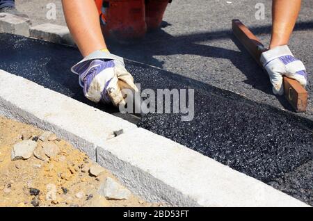 worker is smoothing out asphalt Stock Photo