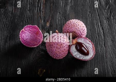 three lychees on a dark wooden background. Stock Photo