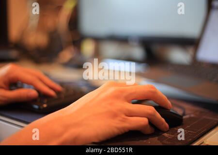 Hand typing on Laptop computer Keyboard holding mouse. information data concepts. Close-up of man hands typing on laptop keyboard. Business man and st Stock Photo