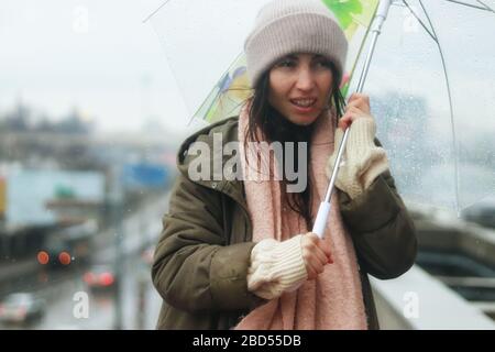 One young woman hiding under umbrella in the sudden heavy and windy spring rain in the city. People in the town during heavy rain. Stock Photo