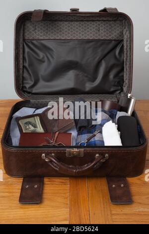 An old brown leather suitcase open showing old items and retro items including an old wallet and key Stock Photo