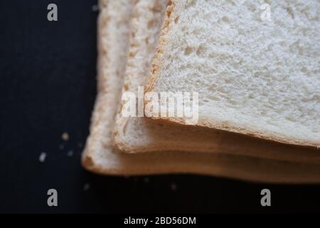 A close up photograph of 3 slices of white bread photographed against a black background Stock Photo