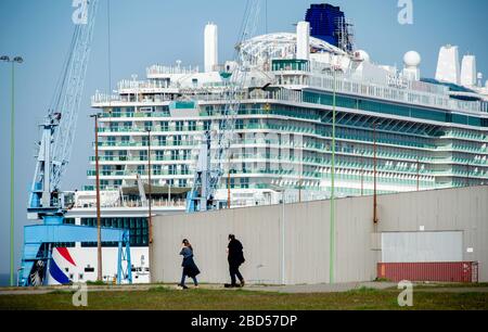 06 April 2020, Bremen, Bremerhaven: Walkers walk along the Weser dyke in front of the cruise ship 'Iona' owned by the British shipping company P&O Cruises. Due to the corona pandemic, the new cruise liner of the Meyer shipyard is to be further equipped at Columbus Quay under strict protective conditions. Photo: Hauke-Christian Dittrich/dpa Stock Photo