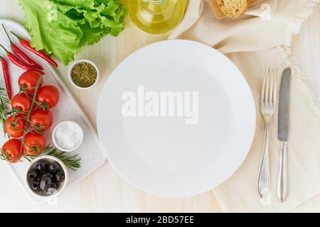 clean empty white plate and vegetables on beige wooden background, top view, copy space Stock Photo