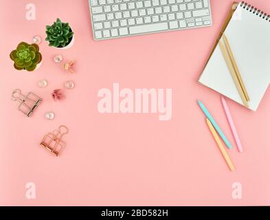 Top view of modern pink woman office desktop with blank notepad, computer. Mock up, empty space. Stock Photo