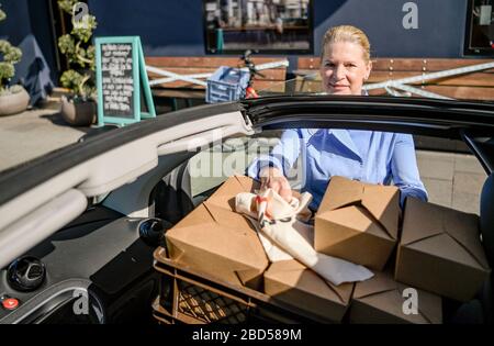 Hamburg, Germany. 07th Apr, 2020. Cornelia Poletto, TV cook, loads several packaged food portions from her restaurant into her car. Poletto regularly cooks food for needy senior citizens and delivers it himself. Credit: Axel Heimken/dpa/Alamy Live News Stock Photo