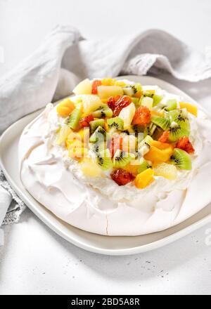 Delicious pavlova meringue cake with kiwi, mango, pineapple, blood orange slices and whipped cream. Selective focus. Stock Photo