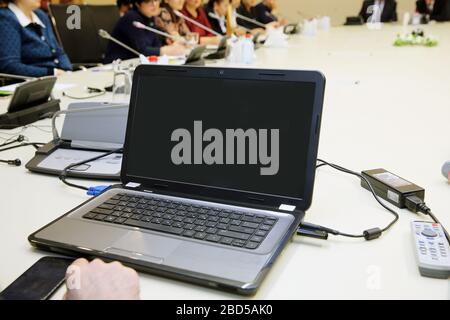 Blank screen desktop computer on the Abstract blurred photo of conference hall or seminar room with attendee background . Laptop on wood table on Stock Photo