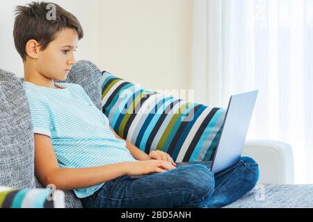 Preteen boy using laptop computer at home. Technology, online learning, distance education, home studying, homework, educational games for kids Stock Photo