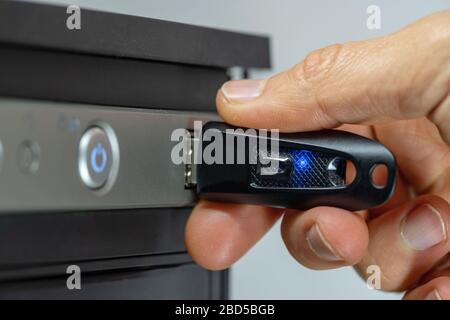 Hand inserting a USB flash drive into a computer. Stock Photo