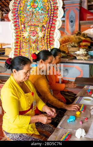 Vertical portrait of women making religious decorations at a temple in Bali, Indonesia. Stock Photo