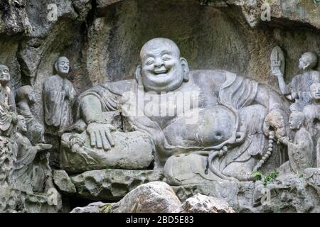 laughing Buddha Maitreya and disciples rock-cut sculpture, Felai Feng grottoes, Lingyin Temple, West Lake, Hangzhou, Chins Stock Photo