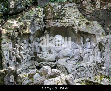 laughing Buddha Maitreya and disciples rock-cut sculpture, Felai Feng grottoes, Lingyin Temple, West Lake, Hangzhou, Chins Stock Photo