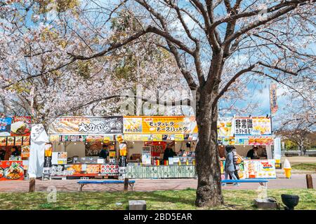Osaka, Japan - April 3, 2019 : Street food stalls with cherry blossoms at Expo '70 Commemorative Park Stock Photo