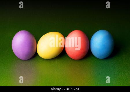 Colorful gypsum easter eggs on green background in a row with reflected color. Stock Photo