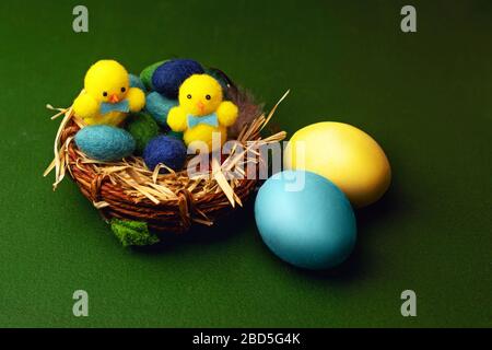 Colorful gypsum easter eggs on green background with basket and chicken toys. Stock Photo