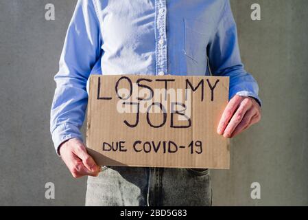 Man office worker in blue shirt with cardboard sign LOST JOB. Jobless, unemployment due covid-19 concept. Asking for money Stock Photo