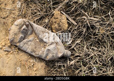 Grey crumpled plastic bottle on the ground. Environmental pollution. Stock Photo