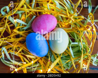 Colorful gypsum eggs on straws with lights, Easter concept. Stock Photo