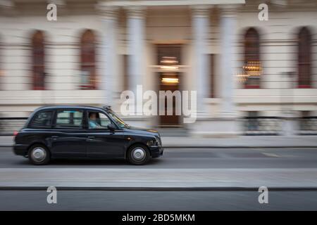 Panned image of London Taxi driving past Oxford and Cambridge Club on Pall Mall, St James, London, England, UK Stock Photo