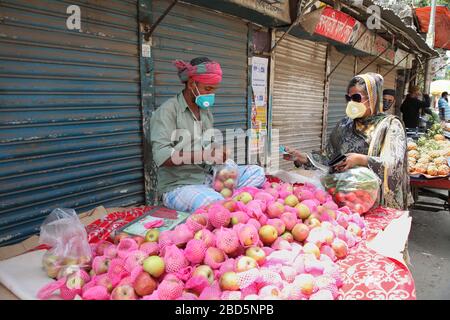 Dhaka, Bangladesh. 07th Apr, 2020. April 7, 2020: A woman is wearing face-mask, gloves and goggles, purchasing apple from a hawker in Dhaka, Bangladesh-he is going to purchase medicines, during the nationwide lockdown of emergency in an attempt to stop the widespread of the coronavirus Covid-19 disease. Credit: ZUMA Press, Inc./Alamy Live News Stock Photo
