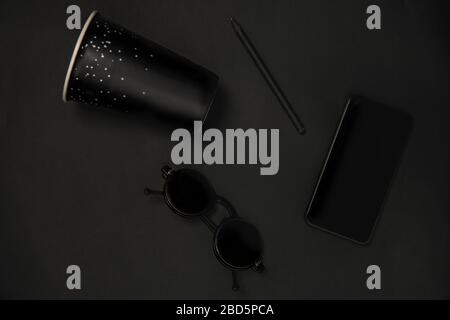 Gadget, coffee and eyewear. Monochrome stylish and trendy composition in black color on studio background. Top view, flat lay. Pure beauty of usual things around. Copyspace for ad. Smartphone. Stock Photo