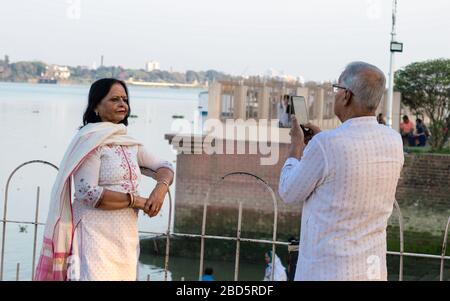 Two active senior couple photographing using mobile phone. Senior man capture the photo and senior woman standing and looking at camera while spending Stock Photo