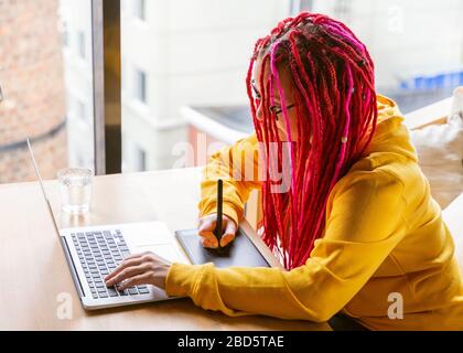 Digital nomad concept. Girl freelancer remotely working on laptop in cafe, coworking. Stock Photo