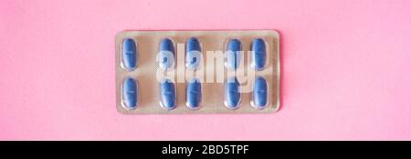 Blue medical pills on pink background. Panorama photo. Stock Photo
