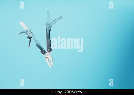 The multitool multi-function tool hovers on a blue background. The concept of an expanded multi-tool with free space. Stock Photo