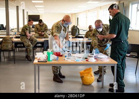 Members of the British Army learn how to apply PPE during training to support the Welsh Ambulance Service NHS Trust (WAST) in the battle against COVID-19 at the Sennybridge Training Camp in Mid Wales. Stock Photo