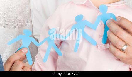 Man's hands holding a blue paper cut group of people, conceptual photo of standing together, teamwork, friendship, and family support Stock Photo
