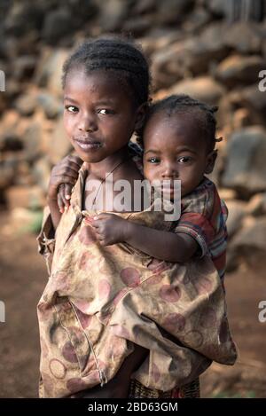 Big brother carries his baby sister, members of the Konso ethnic group or tribe, Gamole village, Abra Minch, Ethiopia. Stock Photo