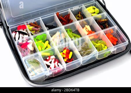 A box with a variety of silicone baits lies in a fishing bag, white background close-up Stock Photo