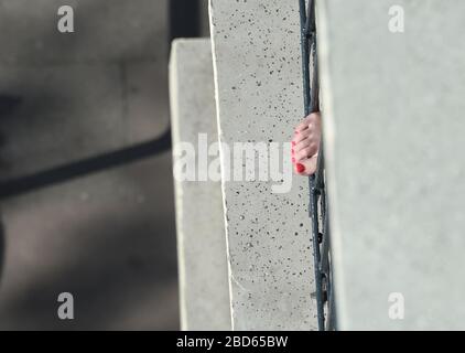 Hamburg, Germany. 07th Apr, 2020. A woman is sunbathing on the balcony and has put her foot through the balcony railing with red painted toenails. Credit: Marcus Brandt/dpa/Alamy Live News Stock Photo