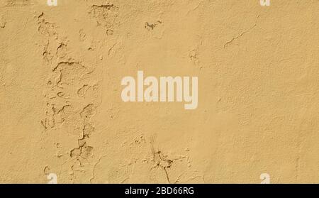 Close-up of a weathered and old concrete wall, yellow paint is peeling off. High resolution abstract full frame textured background. Stock Photo