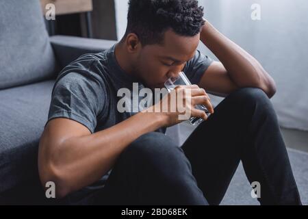 dissatisfied african american man drinking water at home Stock Photo
