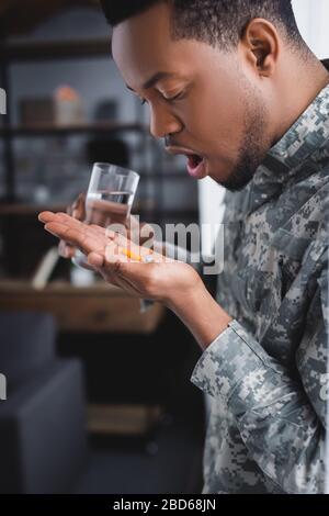 african american soldier taking pills and suffering from PTSD at home Stock Photo
