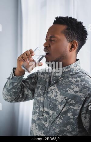 stressed african american soldier drinking water and suffering from PTSD at home Stock Photo
