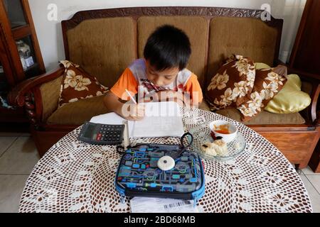 Jakarta, Indonesia - April 2020 : An elementary student is doing homework assignment remotely at home during Covid-19 pandemi. Stock Photo