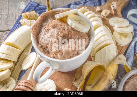 Portioned Banana bread mugcake in small mugs. Easy sweet baking idea, With fresh bananas, nuts, honey and spices on rustic wooden background copy spac Stock Photo