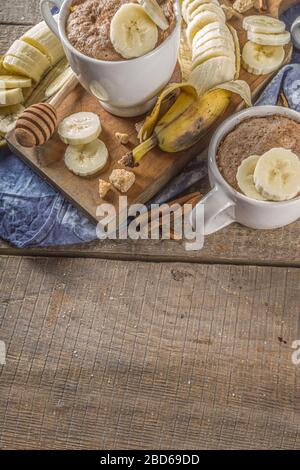 Portioned Banana bread mugcake in small mugs. Easy sweet baking idea, With fresh bananas, nuts, honey and spices on rustic wooden background copy spac Stock Photo