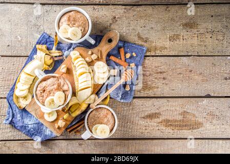 Portioned Banana bread mugcake in small mugs. Easy sweet baking idea, With fresh bananas, nuts, honey and spices on rustic wooden background copy spac Stock Photo