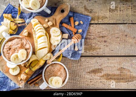 Portioned Banana bread mugcake in small mugs. Easy sweet baking idea, With fresh bananas, nuts, honey and spices on rustic wooden background copy spac Stock Photo