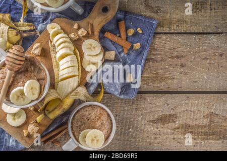 Portioned Banana bread mugcake in small mugs. Easy sweet baking idea, With fresh bananas, nuts, honey and spices on rustic wooden background copy spac Stock Photo