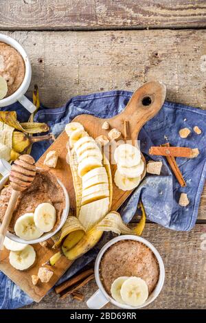 Portioned Banana bread mugcake in small mugs. Easy sweet baking idea, With fresh bananas, nuts, honey and spices on rustic wooden background copy spac Stock Photo