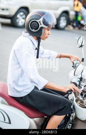 A young Cambodian student makes her way through the streets of Phnom Penh on her scooter. Stock Photo