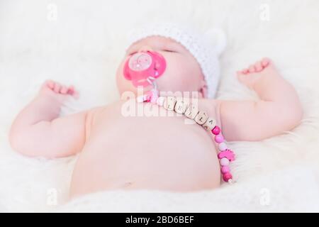 Baby Girl Named Leila Sleeping and Wearing a Wooden Pacifier Chain Stock Photo